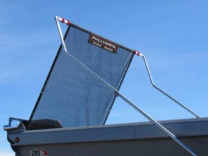 Blue mesh tarp cover raised over a gray roll-off dumpster, supported by a metal frame against a clear blue sky.